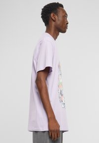 Lilac cotton t-shirt with short sleeves, featuring a center graphic design depicting various cartoon characters. Regular fit, crew neck.