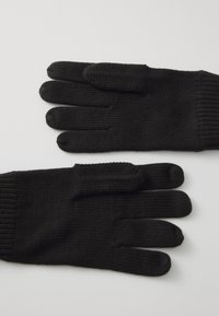 Guantes de punto negros con diseño de cinco dedos. Fabricados en material suave, presentan puños de muñeca acanalados para un ajuste ceñido. Superficie texturizada en toda su extensión.