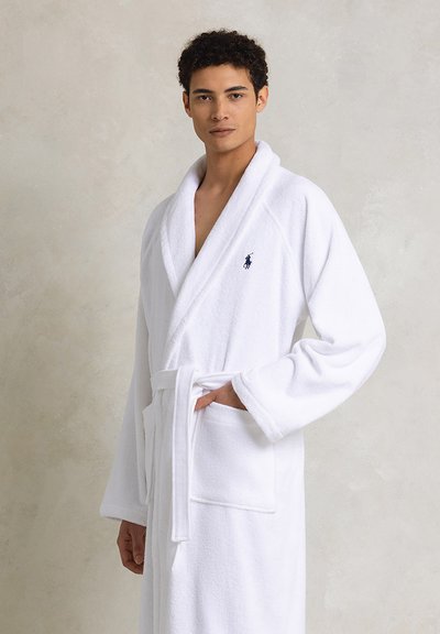 Robe de bain en terry blanc avec col châle, manches longues et ceinture. Comprend deux poches avant et un petit logo brodé.