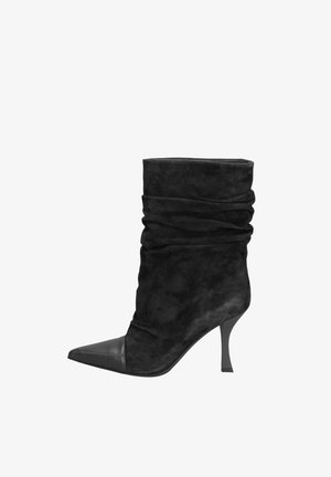 Botte mi-mollet décontractée en daim noir avec bout en cuir pointu et talon haut fin, vue de profil sur fond blanc.