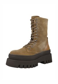 Bota de ante marrón hasta el tobillo con una suela plataforma gruesa de color oscuro, cordones en la parte delantera y un detalle de cuero liso en el talón. Parte superior texturizada con costuras.