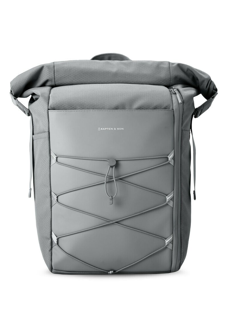 Sac à dos gris avec un design à rabat, fabriqué en tissu durable. Présente un détail en corde élastique à l'avant et des poches zippées sur les côtés.