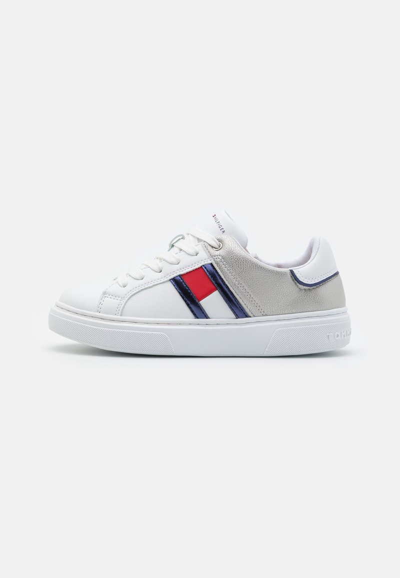 Baskets blanches basses avec un détail rayé rouge, marine et blanc, un accent argenté au talon, des lacets blancs et le nom de la marque embossé sur la semelle.