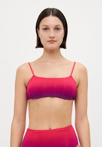 Bikinitopp i gradient rosa tyg med ribbad textur. Har tunna justerbara axelband och en rak halsringning. Slät, minimalistisk design.