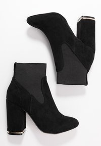Stivali alla caviglia in suede nero con tacco quadrato, dotati di pannelli laterali in elastico e un accento lucido nero sul tacco. Texture liscia.