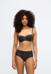 Črna čipkasta spalna garnitura z balkonet modrčkom z valovitim robom in ujemajočimi visokim pasom hlačkami z rastlinskimi vzorci.