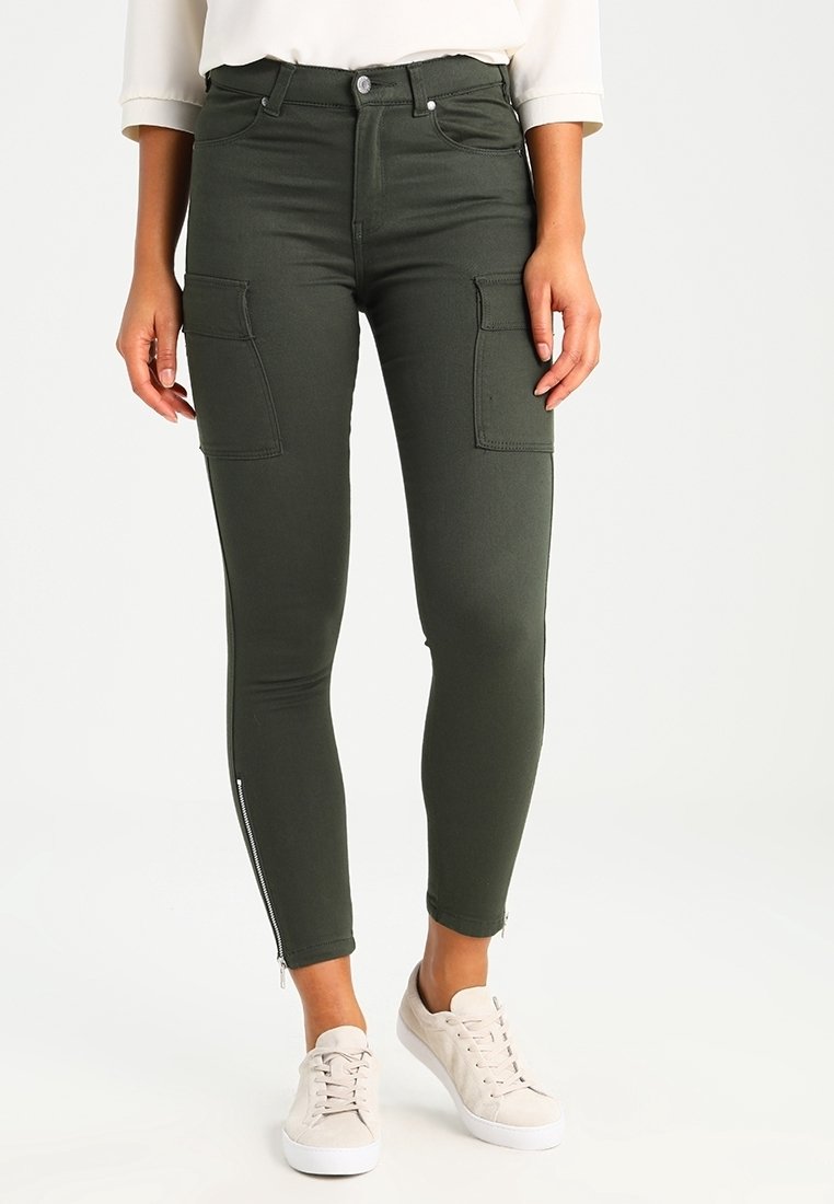 Pantalones cargo verdes con dos bolsillos laterales y detalles con cremallera en los tobillos, fabricados con una tela elástica para un ajuste ceñido.