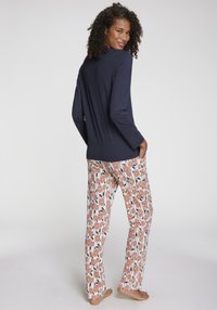 Marinblå långärmad topp med rund hals som är i kombination med mönstrade pyjamasbyxor med orange blommor på vit bakgrund, mjukt tyg.