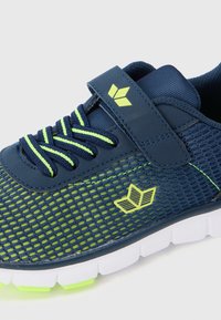 Tengerészkék hálós sneaker zöld díszítésekkel, tépőzáras pánttal, texturált felülettel és fehér talppal, neonzöld részletekkel.