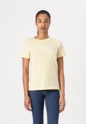 Tricou din bumbac galben cu guler rotund, mâneci scurte și un print alb cu logo-ul "TOMMY HILFIGER EST. 1985" pe față.