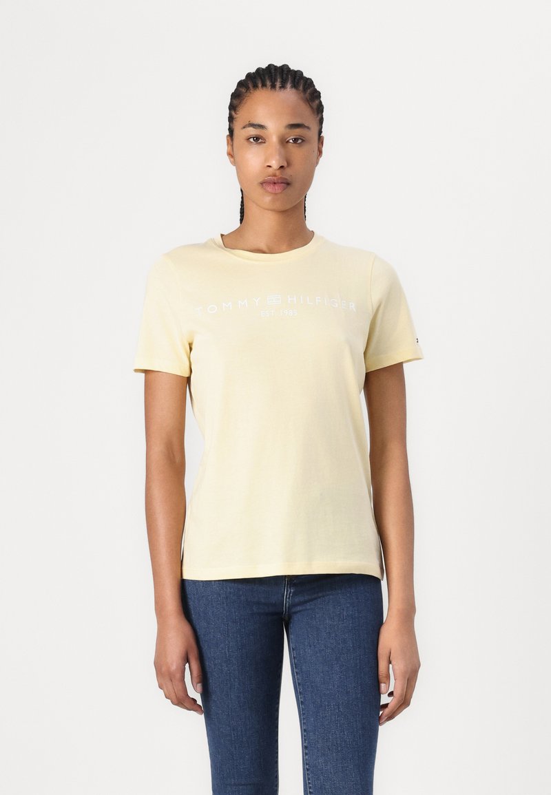 Gul bomulls t-skjorte med rund hals, korte ermer og et hvitt logo-trykk med teksten "TOMMY HILFIGER EST. 1985" på fronten.