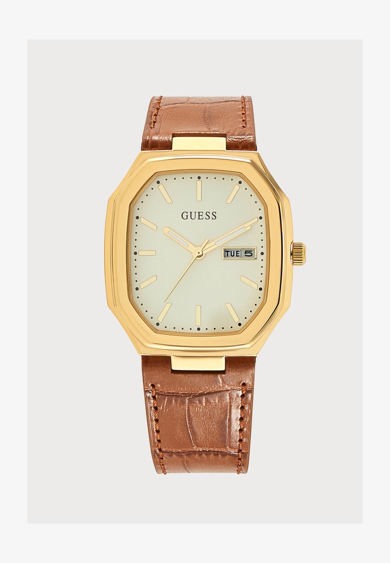 Montre-bracelet rectangulaire Guess dorée avec cadran crème, bracelet en cuir marron, index des heures et affichage jour-date indiquant mardi 5.