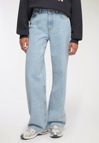 Jeans in denim azzurro chiaro con vita alta, fit ampio e leggero sbiadimento. Presentano un classico design a cinque tasche e dettagli in metallo argentato.