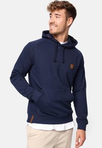 Sudadera azul marino hecha de mezcla de algodón, con un bolsillo frontal tipo bolsa, puños de canalé y un parche de cuero con el logotipo cerca del pecho.
