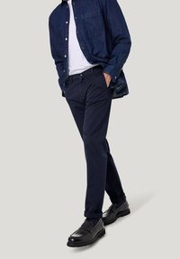 Navyblauwe slim-fit broek gemaakt van een katoenmix, gecombineerd met een denim shirt en gepolijste zwarte schoenen.