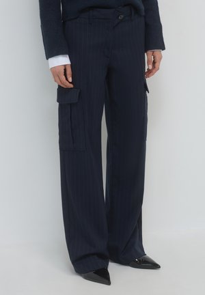 Marineblau gestreifte Cargo-Hosen mit zwei Seitentaschen, weitem Bein und glatter Textur; kombiniert mit schwarzen spitzen Pumps.