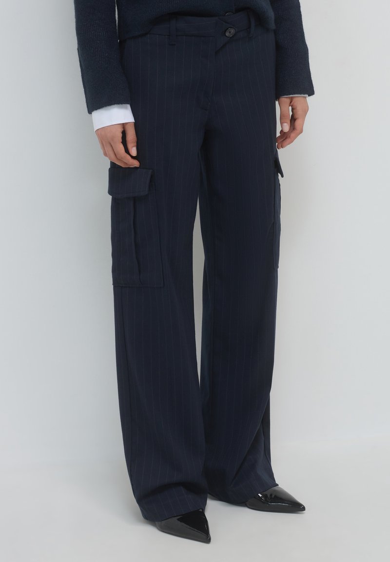 Marineblau gestreifte Cargo-Hosen mit zwei Seitentaschen, weitem Bein und glatter Textur; kombiniert mit schwarzen spitzen Pumps.