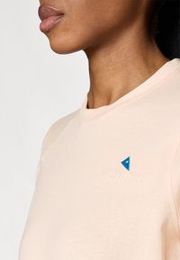 Lichtroze t-shirt met een ronde halslijn, voorzien van een blauw driehoekig logo en geborduurde merknaam op de borst. Zachte stofstructuur.