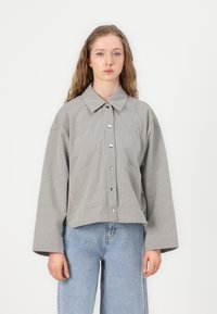 Stripet skjorte med krage, droppede skuldre og cropped pasform; grå og hvidt stof med en glat tekstur.