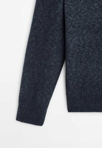 Manche de pull en laine tricotée bleu foncé avec bord-côtes sur fond blanc uni.