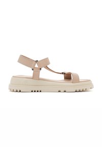 Sandales en cuir beige avec deux larges brides et un design en T. Semelle en caoutchouc épaisse de couleur écrue avec un motif de grip texturé.