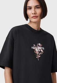 T-shirt nera oversized in cotone, con un design floreale e il logo bianco "ALLSAINTS" al centro. Maniche corte, scollo rotondo.
