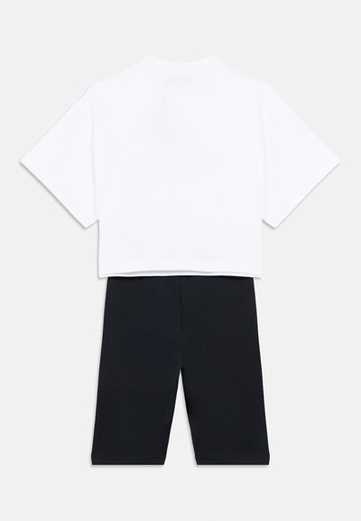 Λευκό crop top με κοντά μανίκια και στρογγυλεμένο ντεκολτέ, συνδυασμένο με μαύρες βερμούδες μέχρι το γόνατο από μαλακό ύφασμα.