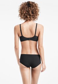 Svart underklädesset med enkel design, mjukt tyg, justerbara band och sömlös finish, sett bakifrån.