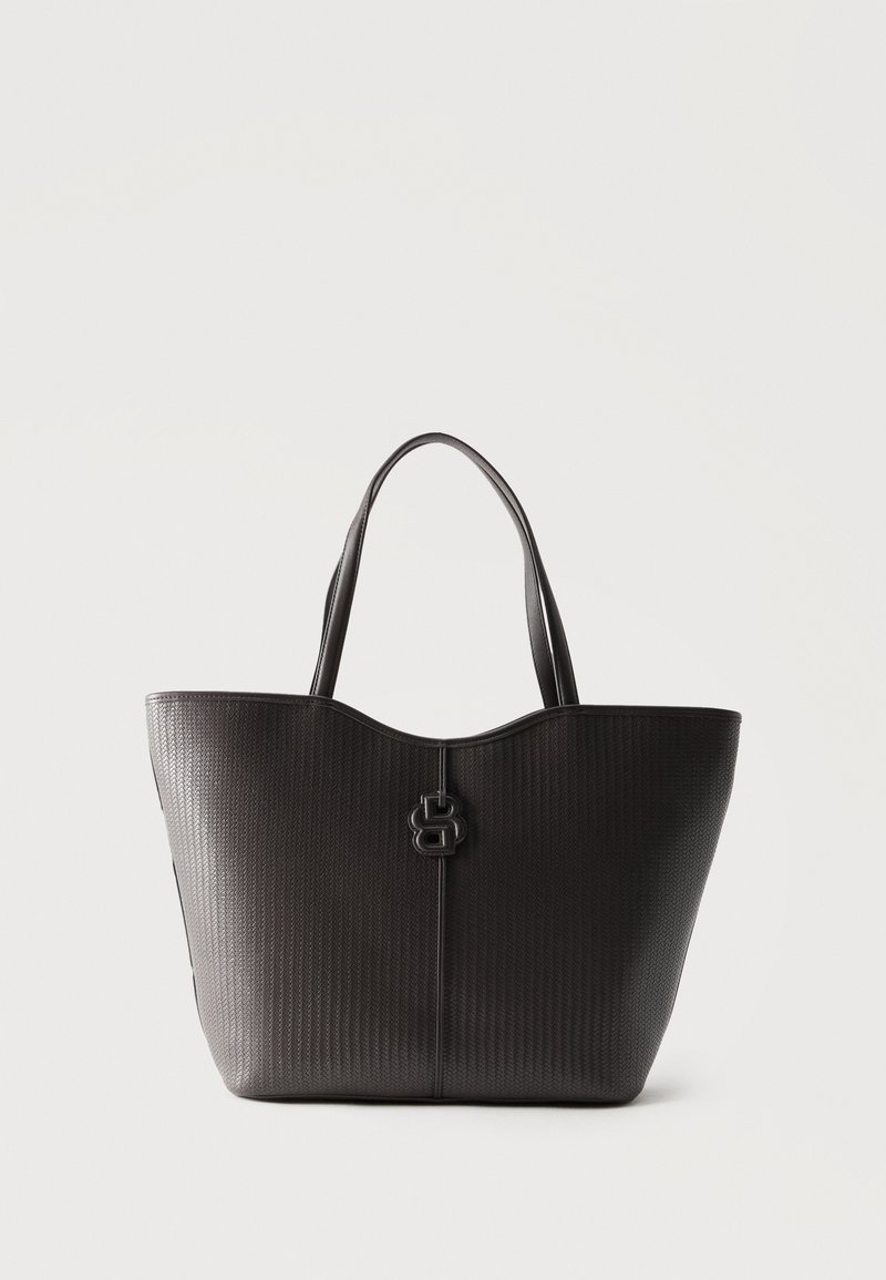 Μαύρη υφασμάτινη δερμάτινη τσάντα tote με διπλές λαβές και κεντρικό διακοσμητικό κούμπωμα σε μονόχρωμο φόντο.