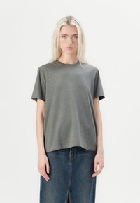 T-shirt gris à manches courtes en tissu doux et lisse, avec une coupe décontractée. Encolure ronde, associé à une jupe en denim avec une fente frontale.