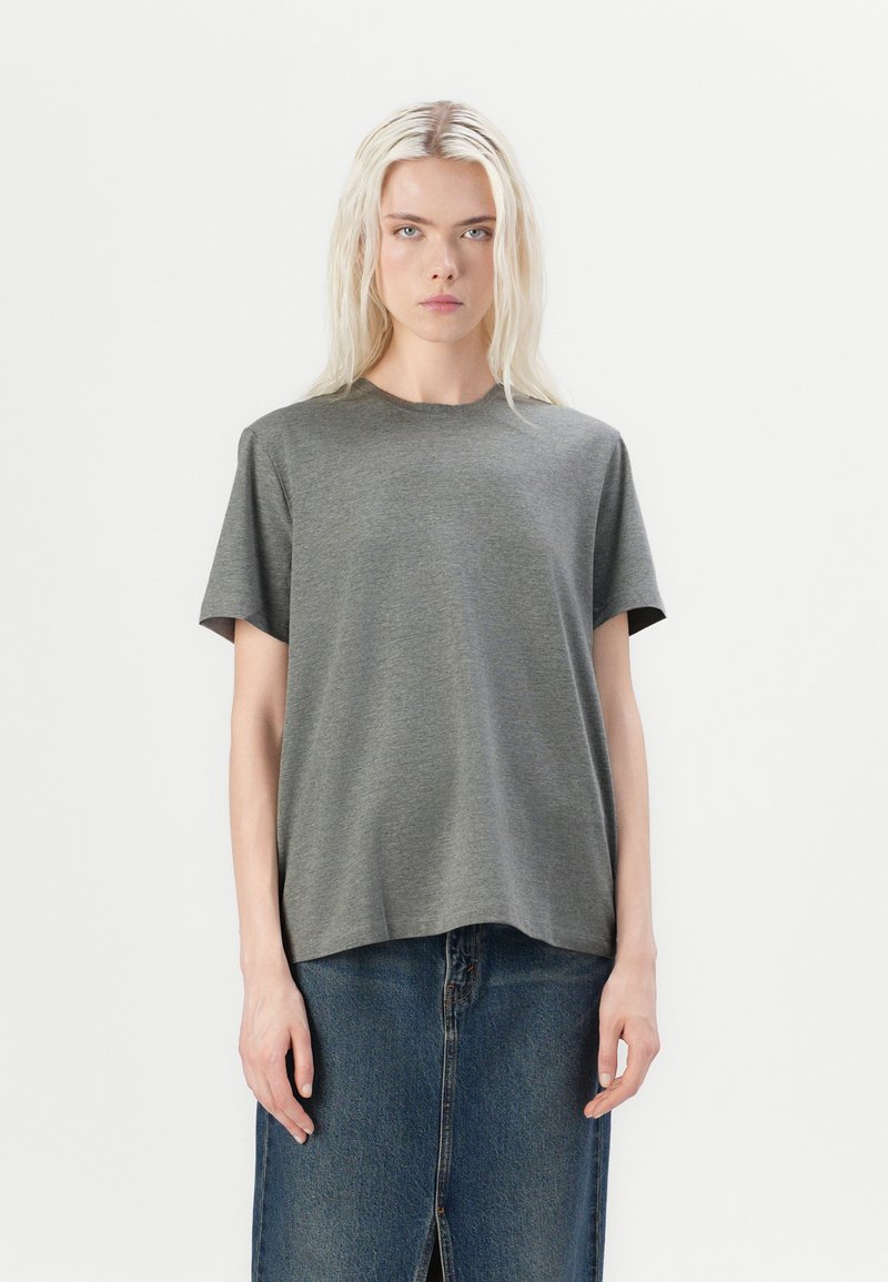 T-shirt gris à manches courtes en tissu doux et lisse, avec une coupe décontractée. Encolure ronde, associé à une jupe en denim avec une fente frontale.