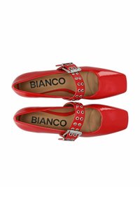 Scarpe in vernice rossa con punta quadrata, dotate di una larga cinghia alla caviglia con hardware in argento e ritagli circolari. Nome del marchio "BIANCO" visibile all'interno.