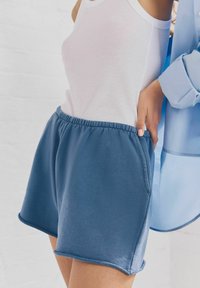 Pantaloni corti in misto cotone blu con vita elastica e tasche laterali, caratterizzati da una texture morbida e un orlo pulito.