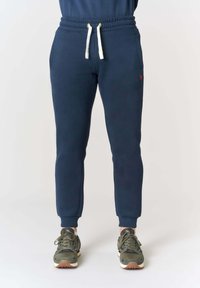 Pantaloni jogger blu navy con fascia elastica in vita e coulisse bianca. Presentano tasche laterali e un piccolo logo rosso sulla coscia sinistra.
