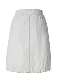 Falda blanca hasta la rodilla con cintura elástica y dobladillo fruncido, con una costura vertical central y una pequeña etiqueta rectangular con logo en la cintura.