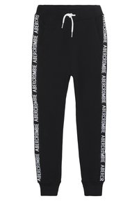 Zwarte joggingbroek met witte trekkoord en de tekst "Abercrombie" die verticaal langs beide buitenste naden van de benen loopt.