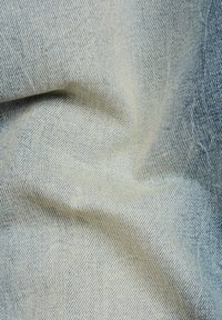 Light blue denim fabric with a fine twill weave, showcasing a soft texture and subtle fading, creating a smooth, wrinkled appearance.