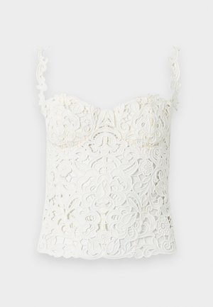 Λευκό crop top από δαντέλα με περίτεχνα λουλουδένια και σπιράλ σχέδια, με λεπτούς, διακοσμητικούς ιμάντες ώμων και εφαρμοστό σχεδιασμό στο στήθος.