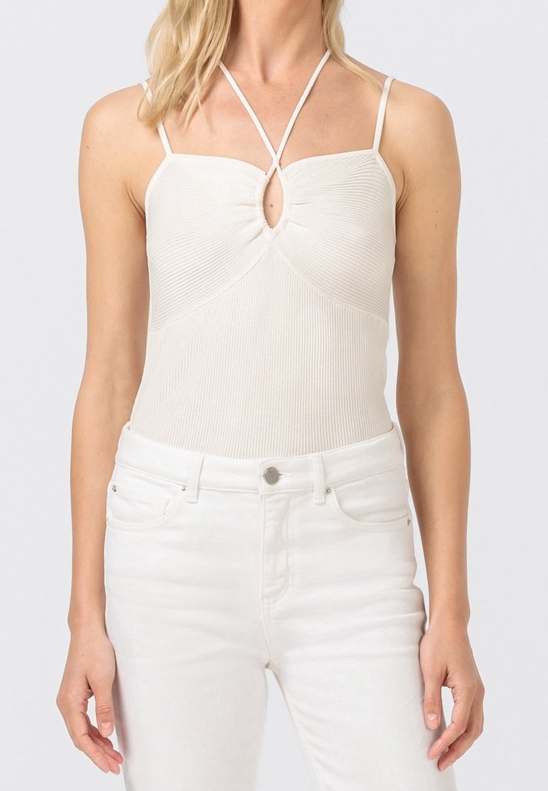 Białe body w prążki z detalem w kształcie dziurki w dekolcie i cienkimi ramiączkami, zestawione z białymi dżinsami. Gładka faktura i dopasowany krój.