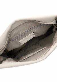 Interno di una borsa leggera color beige con una tasca con zip, fodera in tessuto e un'etichetta con la scritta "EMILY & NOAH." Texture liscia e design pulito.
