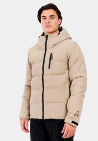 Chaqueta acolchada color beige con cierre frontal, capucha ajustable y puños elásticos. Presenta detalles en negro y un logotipo sutil en el pecho.