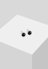 Orecchini a perno in argento caratterizzati da pietre nere rotonde e sfaccettate con finitura lucida, montate in una cornice circolare. Design compatto e moderno.