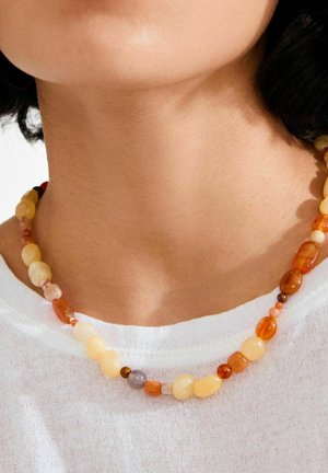 Collana di perline con pietre lisce di forma irregolare in tonalità di giallo, arancione e un accenno di grigio, infilate insieme con piccoli accenti.