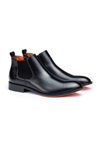 Stivaletti neri in pelle con pannelli laterali elasticizzati, tacco piatto e fodera arancione, caratterizzati da un design elegante e una texture liscia.
