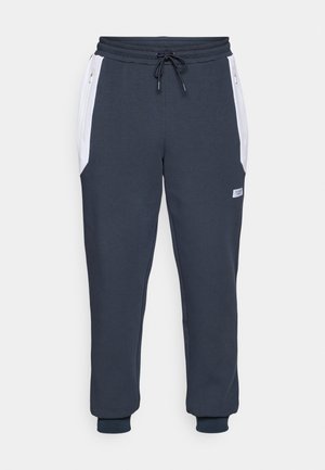 Pantaloni jogger bleumarin cu talie elastică, șnur de ajustare și buzunare laterale albe. Prezintă manșete ribbate și o etichetă mică de marcă pe coapsă.