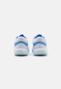 Sneakers bianchi con accenti azzurri chiari, caratterizzati da una texture in rete e colletto imbottito, progettati per comfort e supporto.