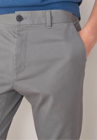 Gray tailored pants with a smooth, textured fabric. Features a front pocket, belt loops, and a single button closure at the waistband.