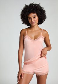 Set de pijamale din satin piersici, cu dantelă, format dintr-un top tip camisole și pantaloni scurți. Textura netedă și accentele delicate din dantelă îmbunătățesc designul.