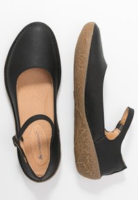 Svarta läder Mary Jane-skor med rund tå, mandelformad öppning, texturerad tan-färgad innersula och en flexibel brun gummisula.