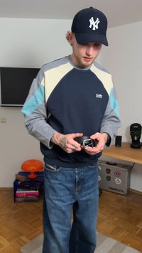 Bomullssweatshirt med fargeblokkdesign i marineblå, lysegrå og grønnblå; kombinert med blå denimjeans; person som justerer et belte.